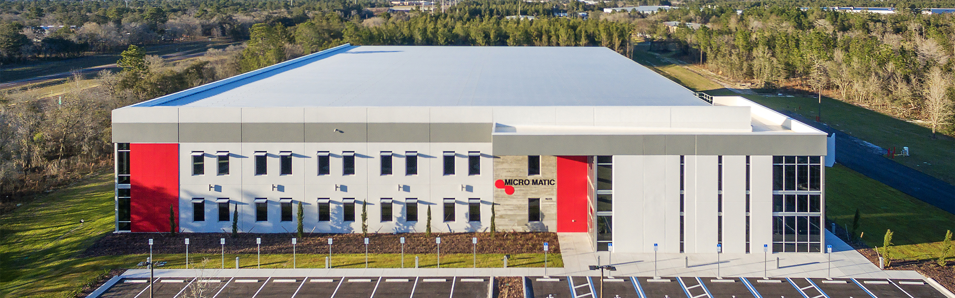 Aerial view of a metal industrial building with white wall panels and red accent bays